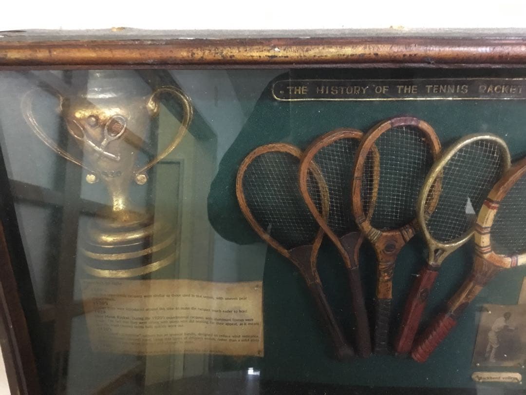 アンティークなテニスラケットの歴史と変遷について解説している彫刻が収められた額装