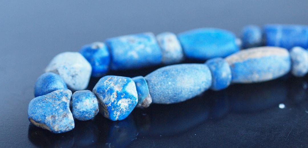 古代濃紺ラピスの管玉や丸玉をほぼ左右対称に編み、トップに斧型や多面体、80個の連