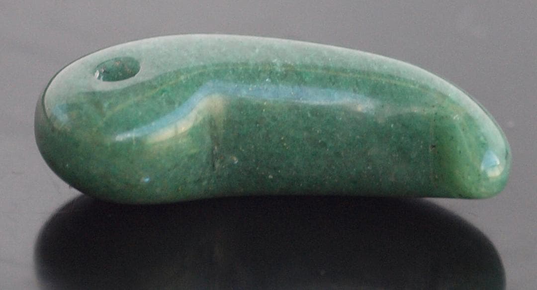 光にかざすと薄緑の細い帯状紋が出現、頭・胴の間には沈線、ずんぐり形の勾玉　沖縄の